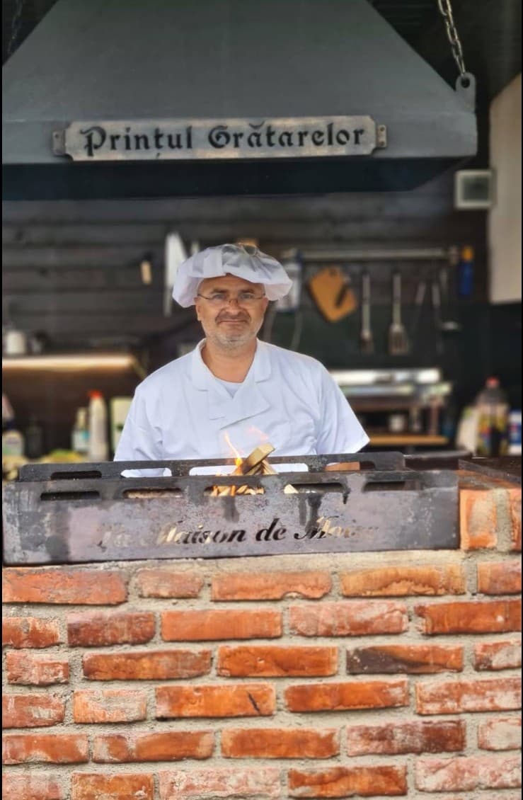 The host at the grill, under the sign “Prințul Grătarelor”