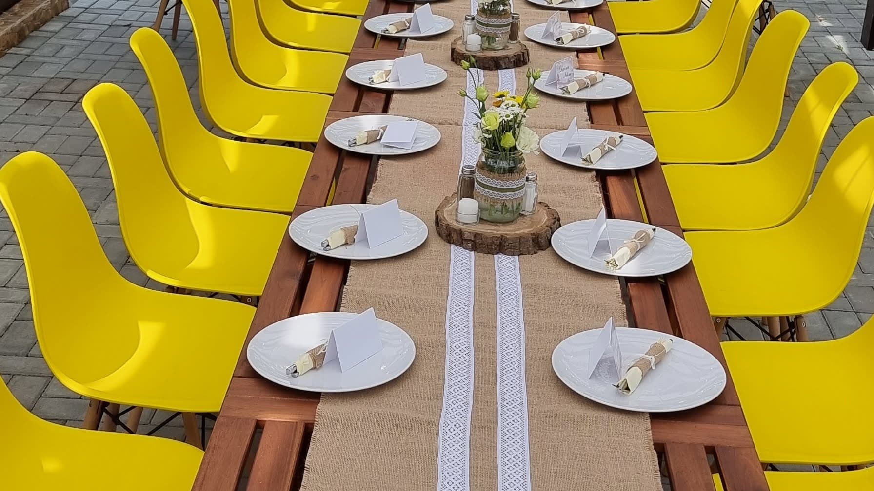 A long table laid for an event, with yellow chairs